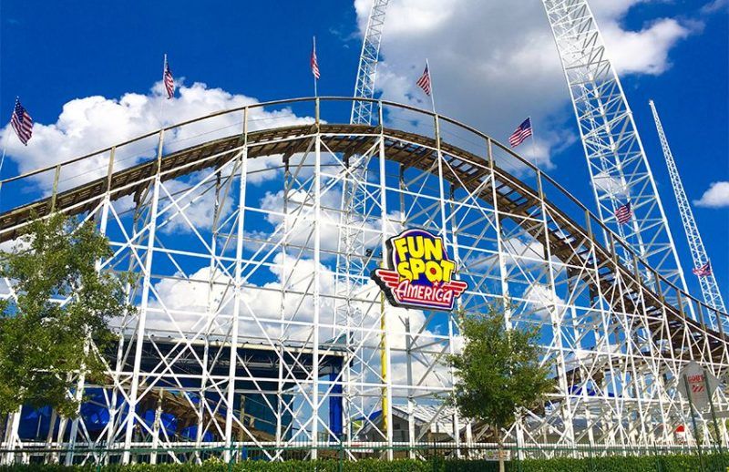 A roller coaster at an amusement park with a blue sky in the background.