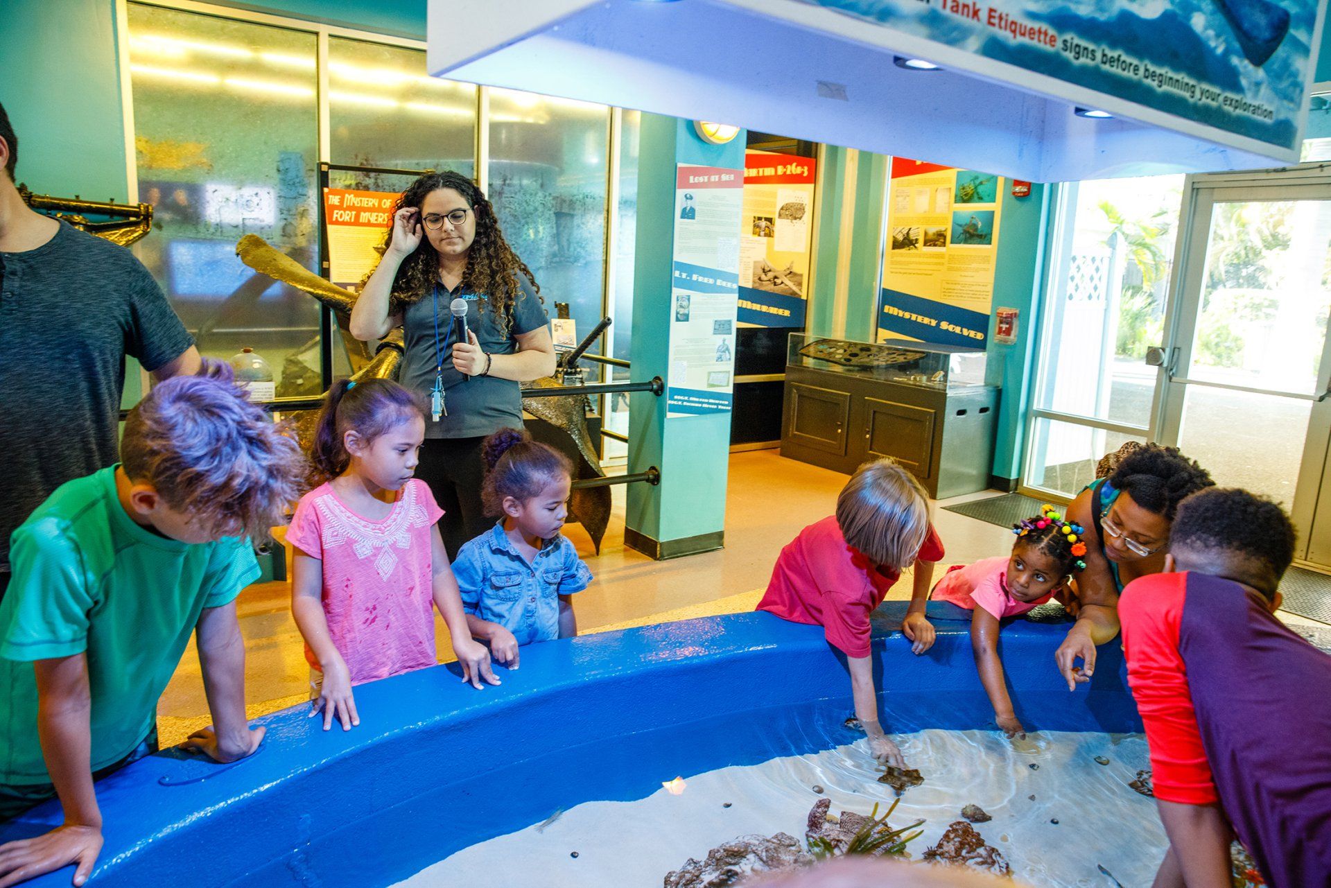 A group of children are looking at sea turtles in an aquarium.