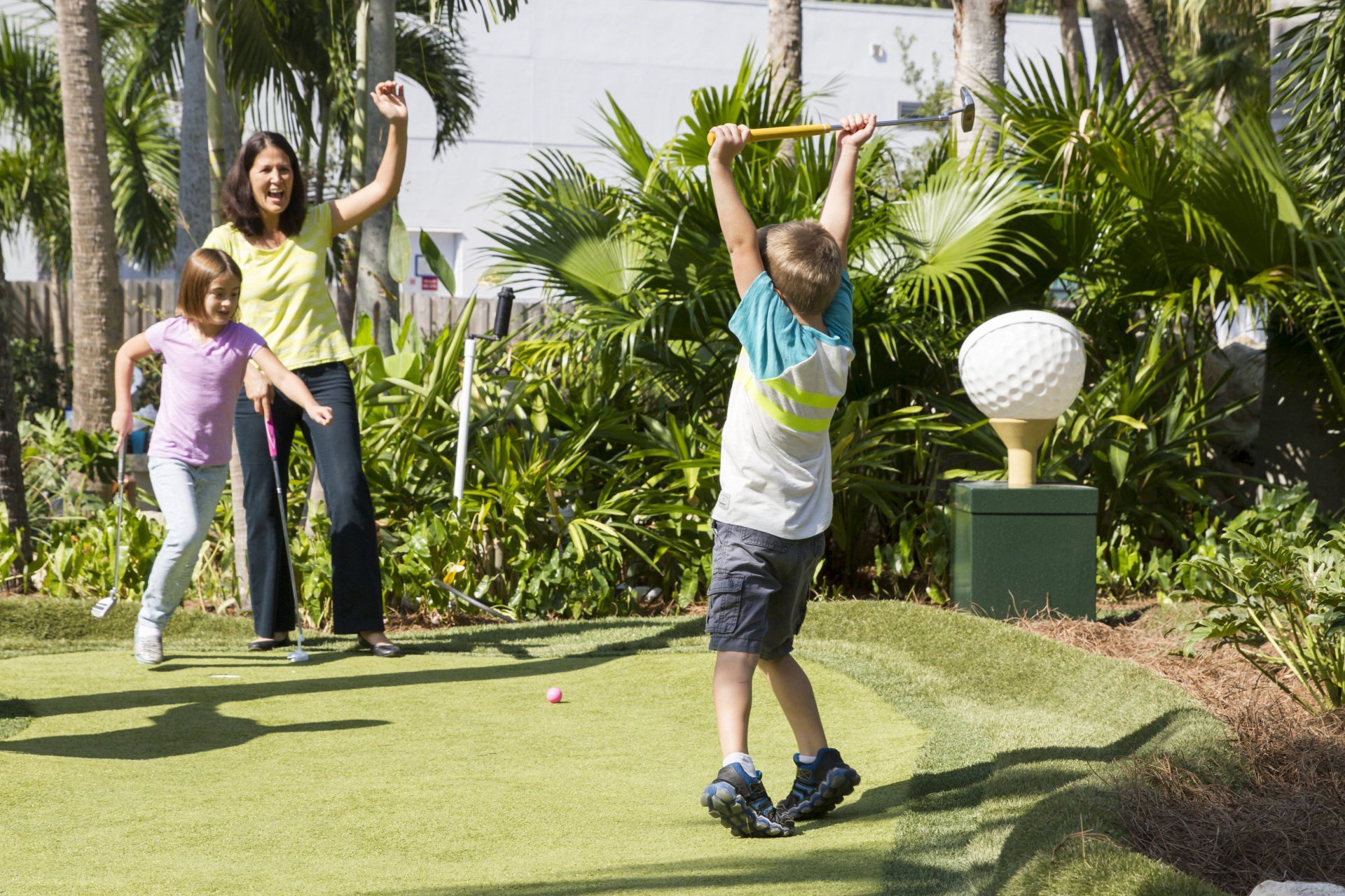 A woman and two children are playing a game of golf