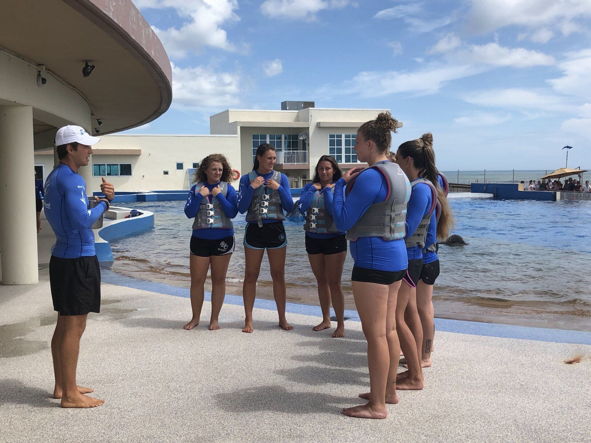A group of people standing on a beach with a man talking to them