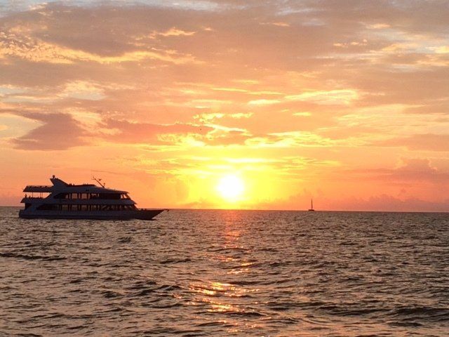 A boat is floating on top of a body of water at sunset.