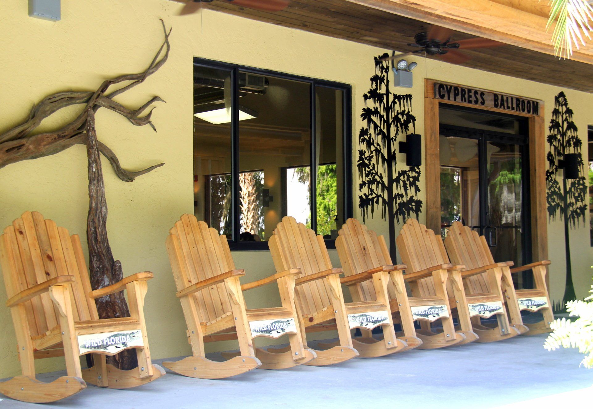 A row of wooden rocking chairs in front of a building that says happiness kitchen