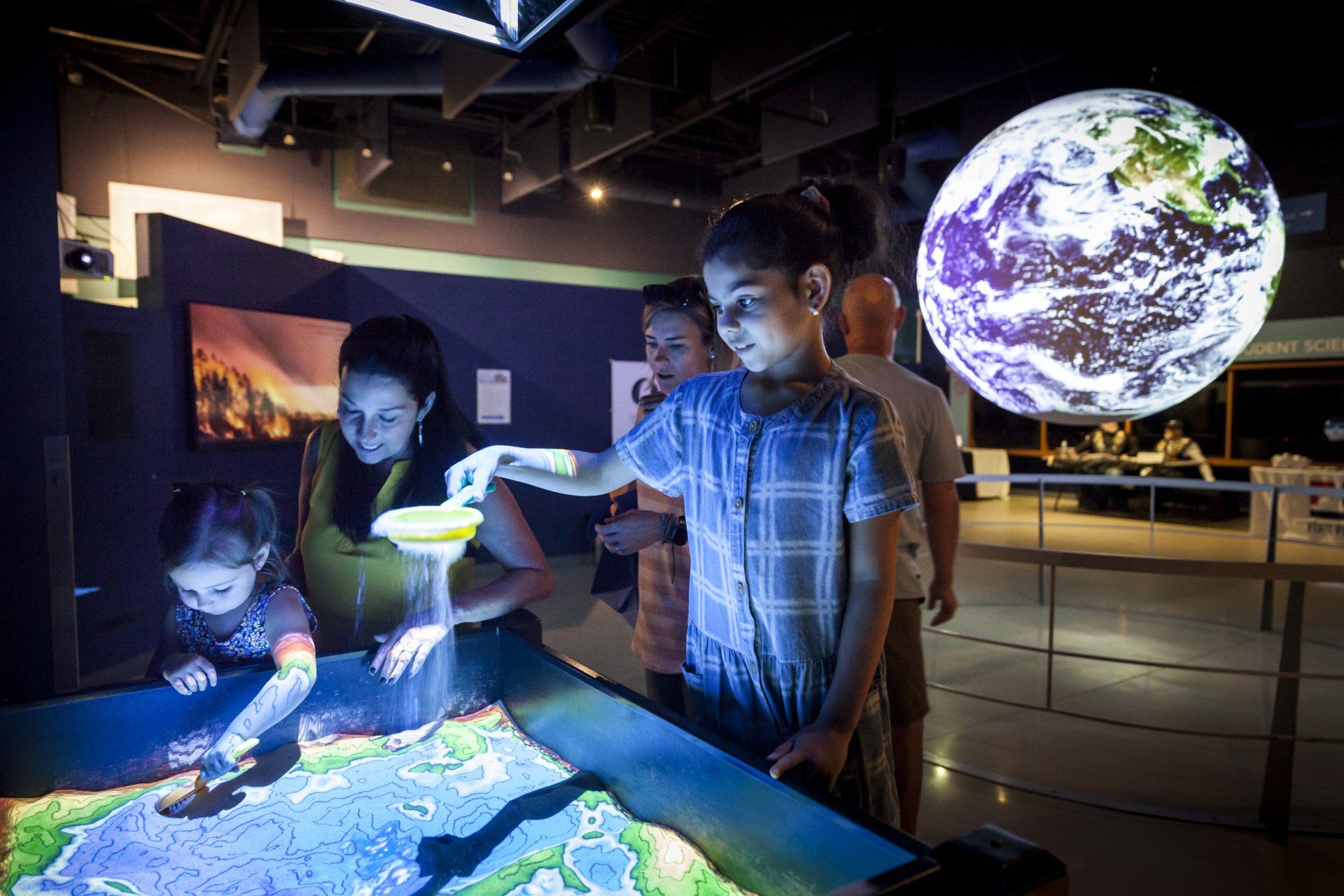 A group of children are looking at a map of the earth on a table.