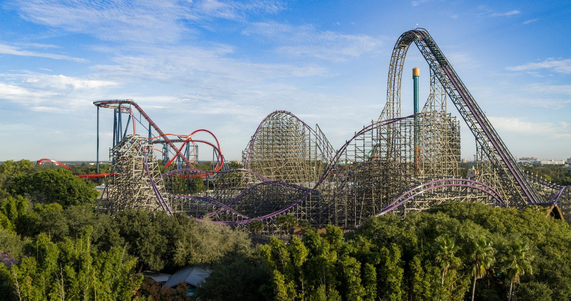 An aerial view of a roller coaster at an amusement park surrounded by trees.