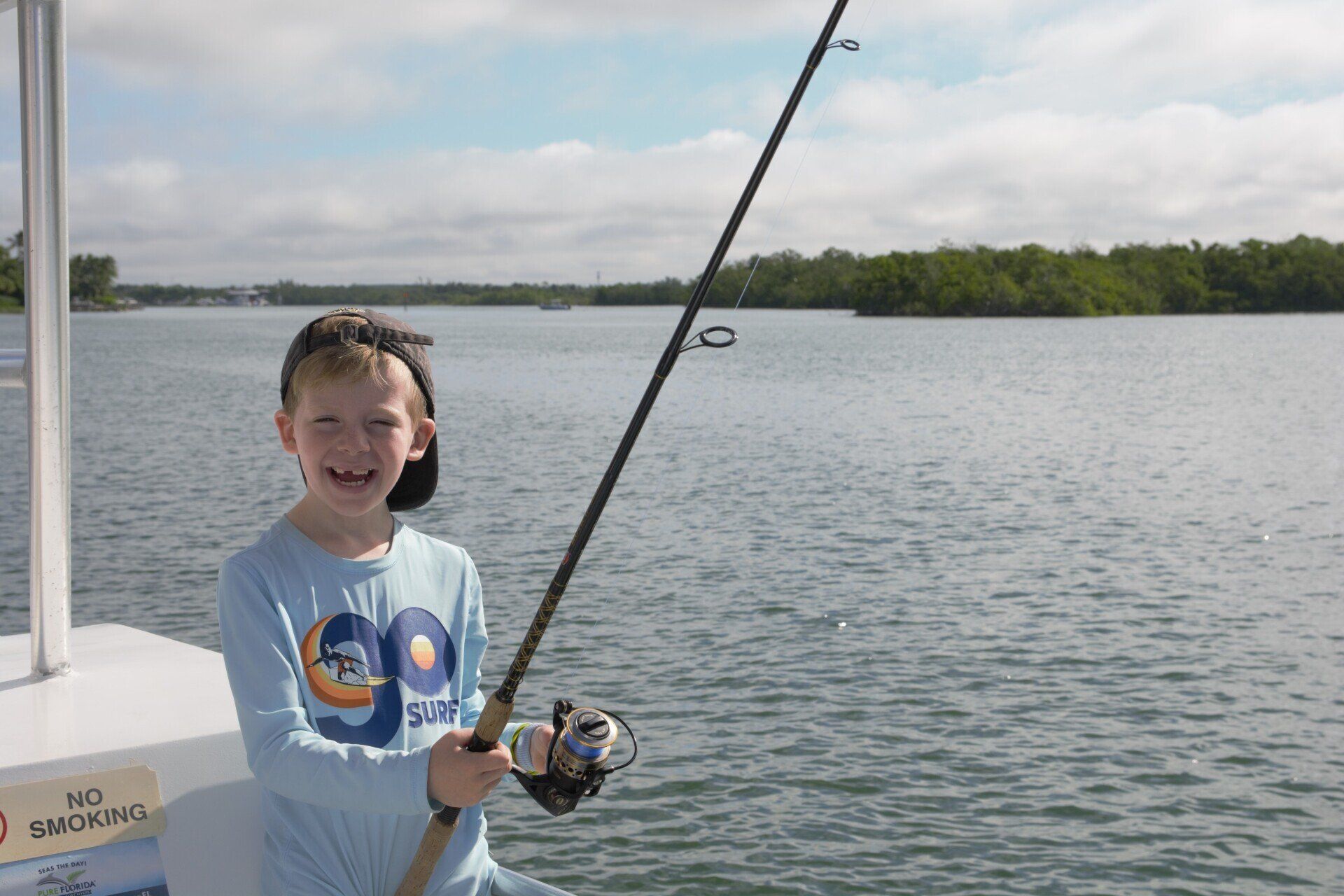 A young boy is holding a fishing rod on a boat.