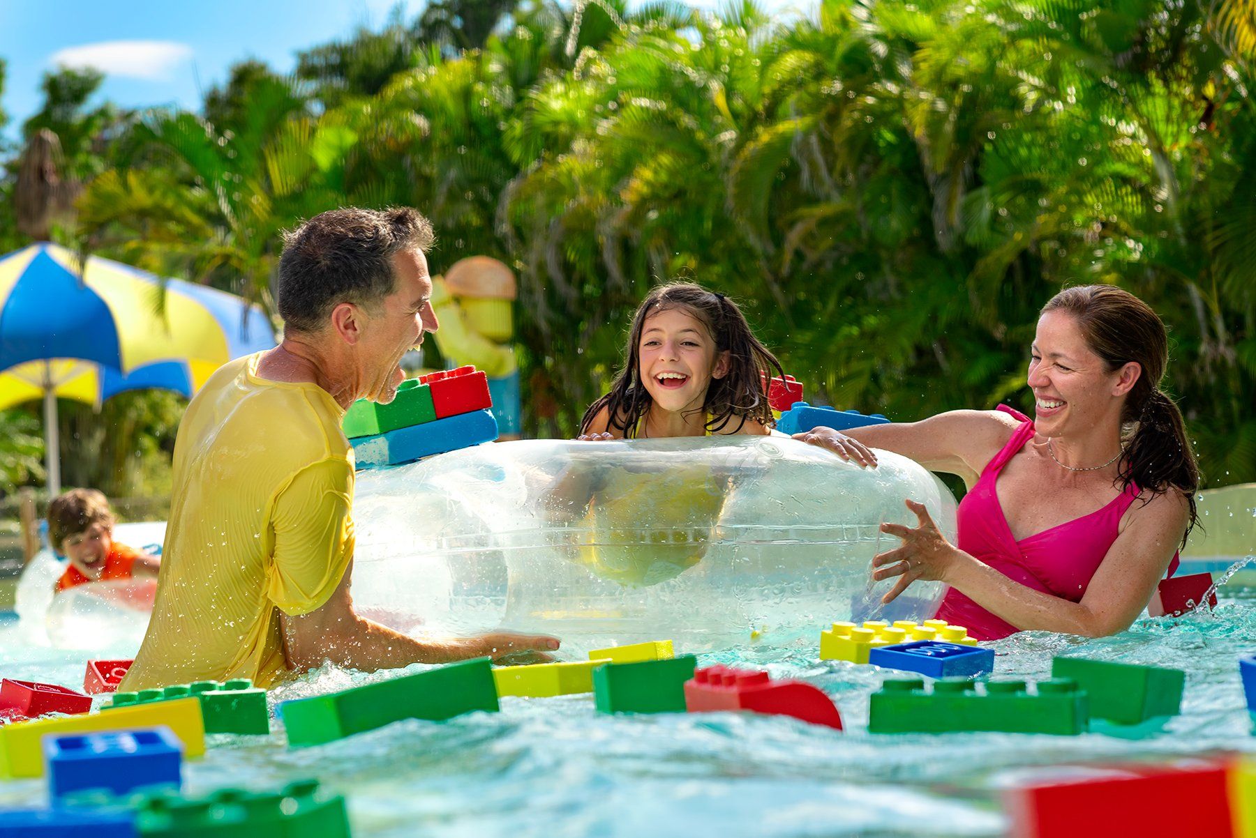 A family is playing in a swimming pool filled with lego blocks.