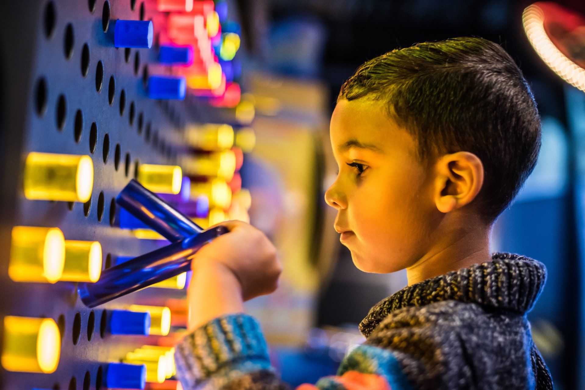 A young boy is playing with a wall of lights.