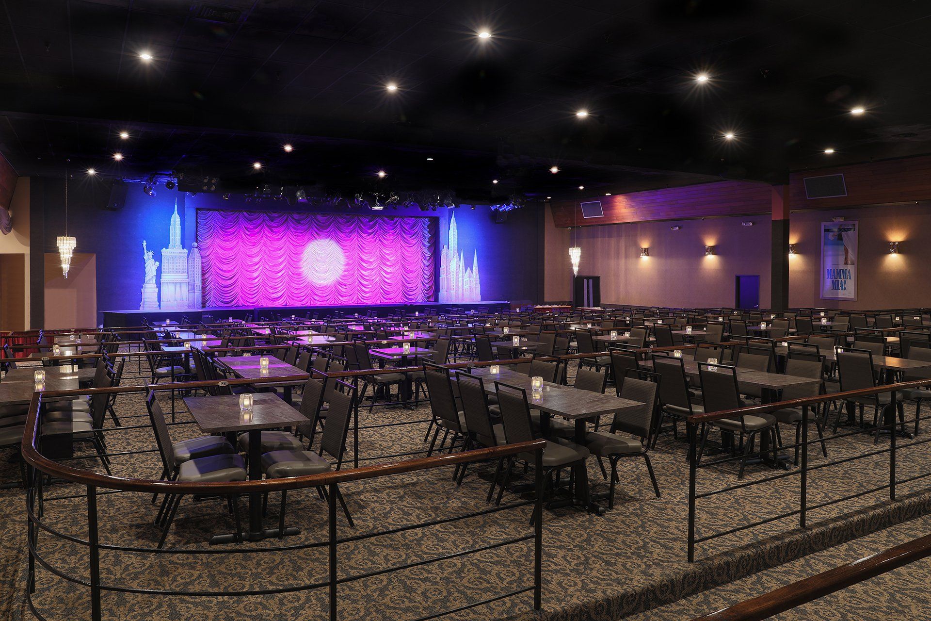 A large empty auditorium with tables and chairs and a stage.