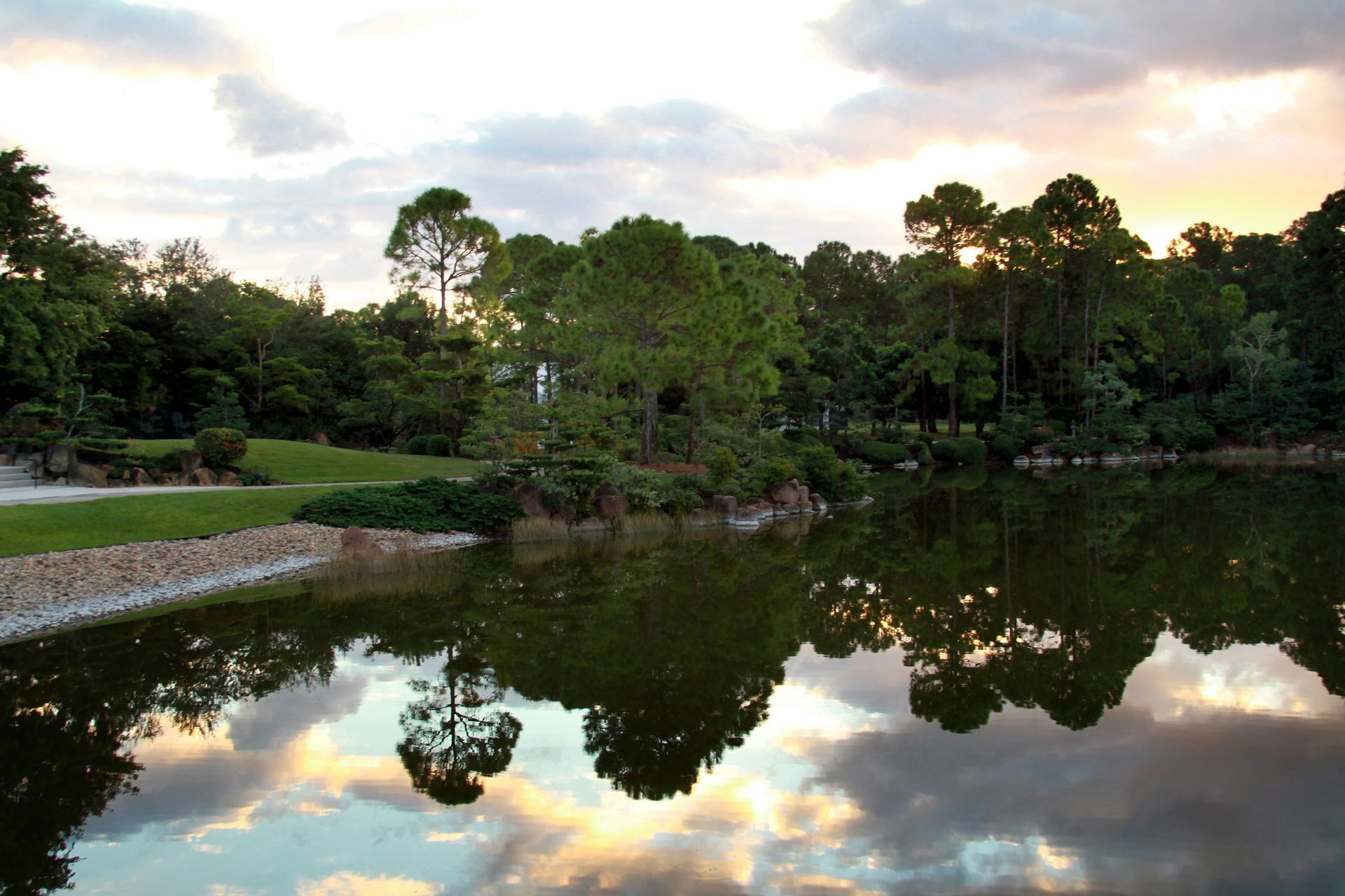 A lake surrounded by trees with a sunset in the background