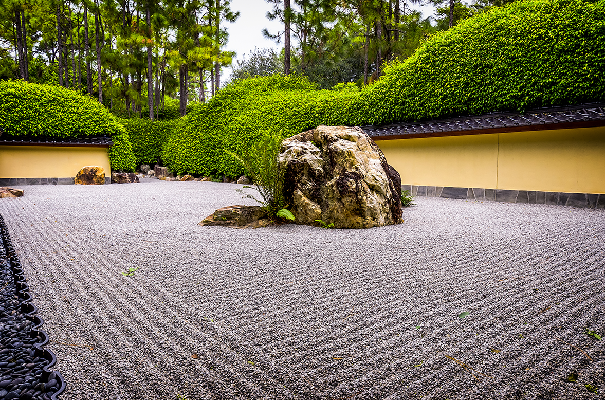 A large rock is sitting in the middle of a gravel garden.