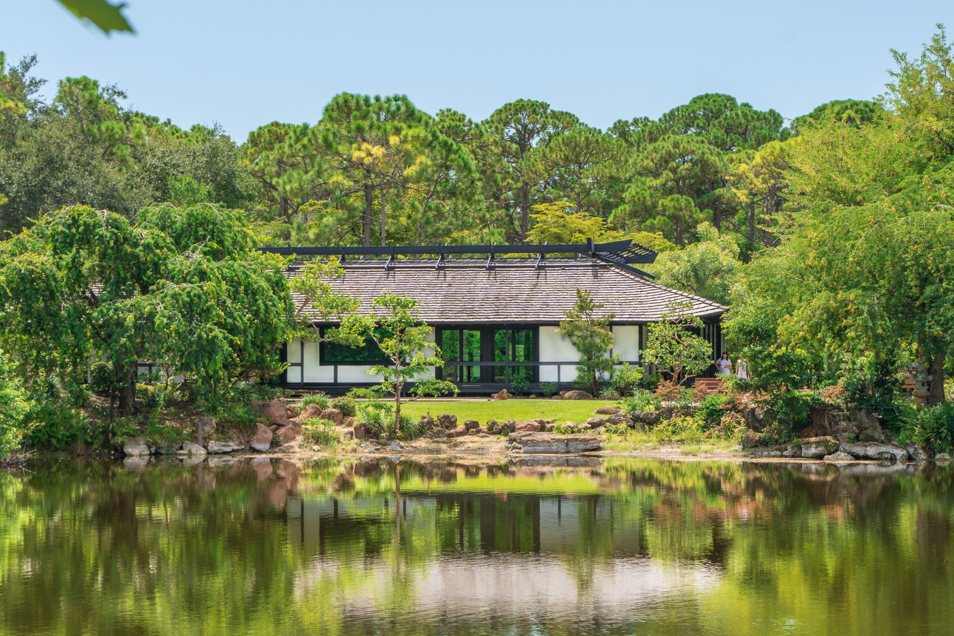 A house is sitting on the shore of a lake surrounded by trees.