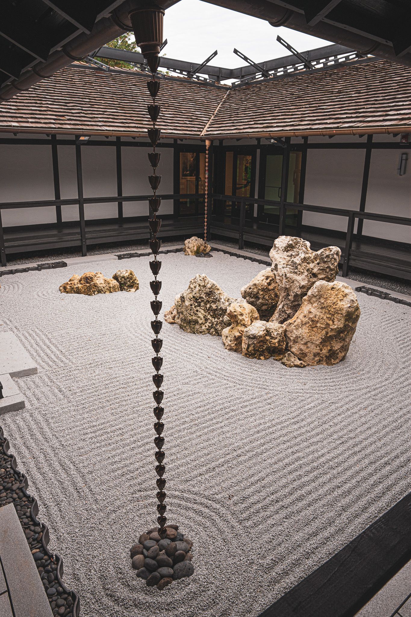 There is a chain hanging from the ceiling in the middle of a rock garden.