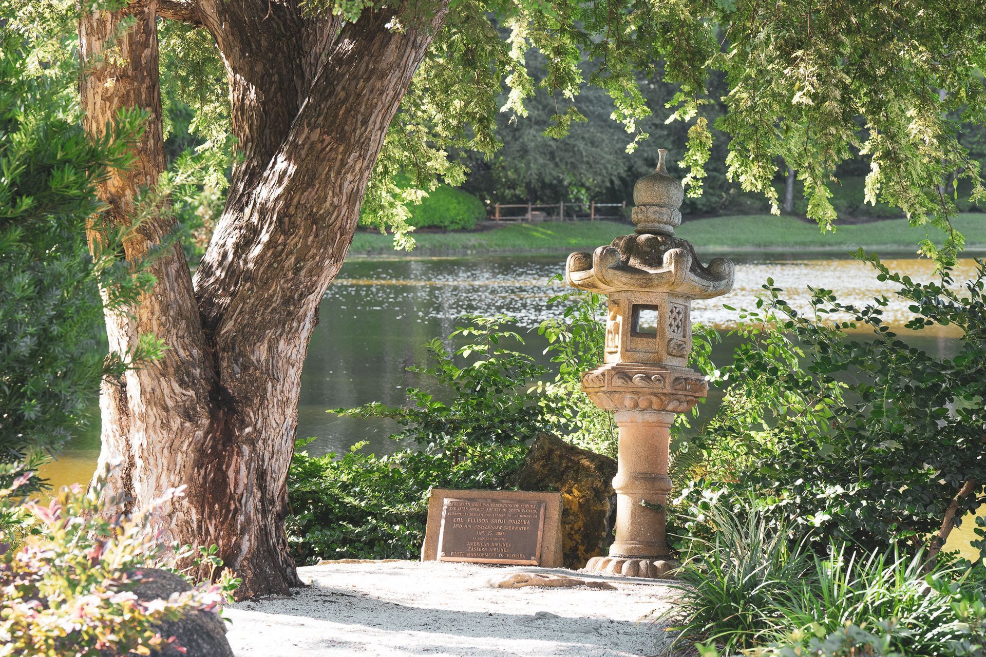 A stone lantern is in the middle of a park next to a tree