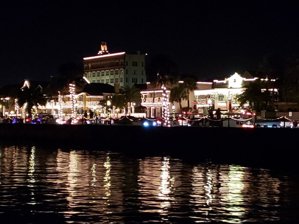 A city lit up at night is reflected in the water