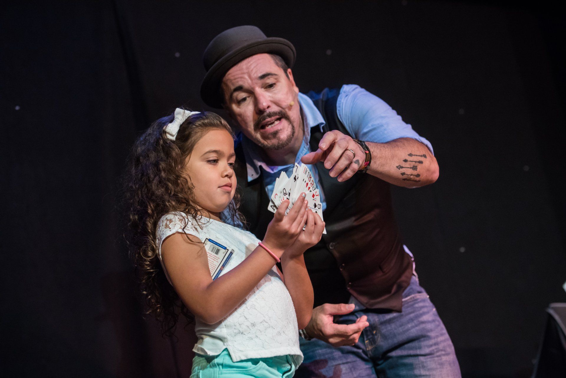 A man and a little girl are playing cards on a stage.