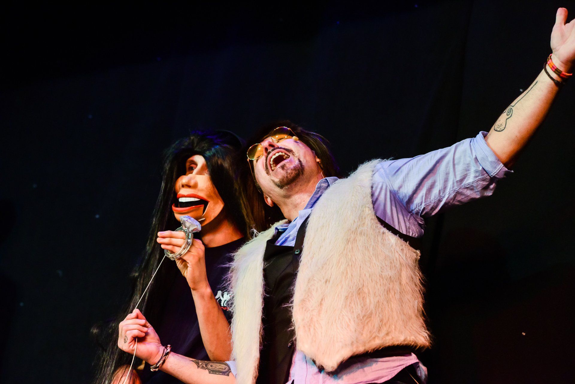 A man and a woman are standing next to each other on a stage with their arms outstretched.
