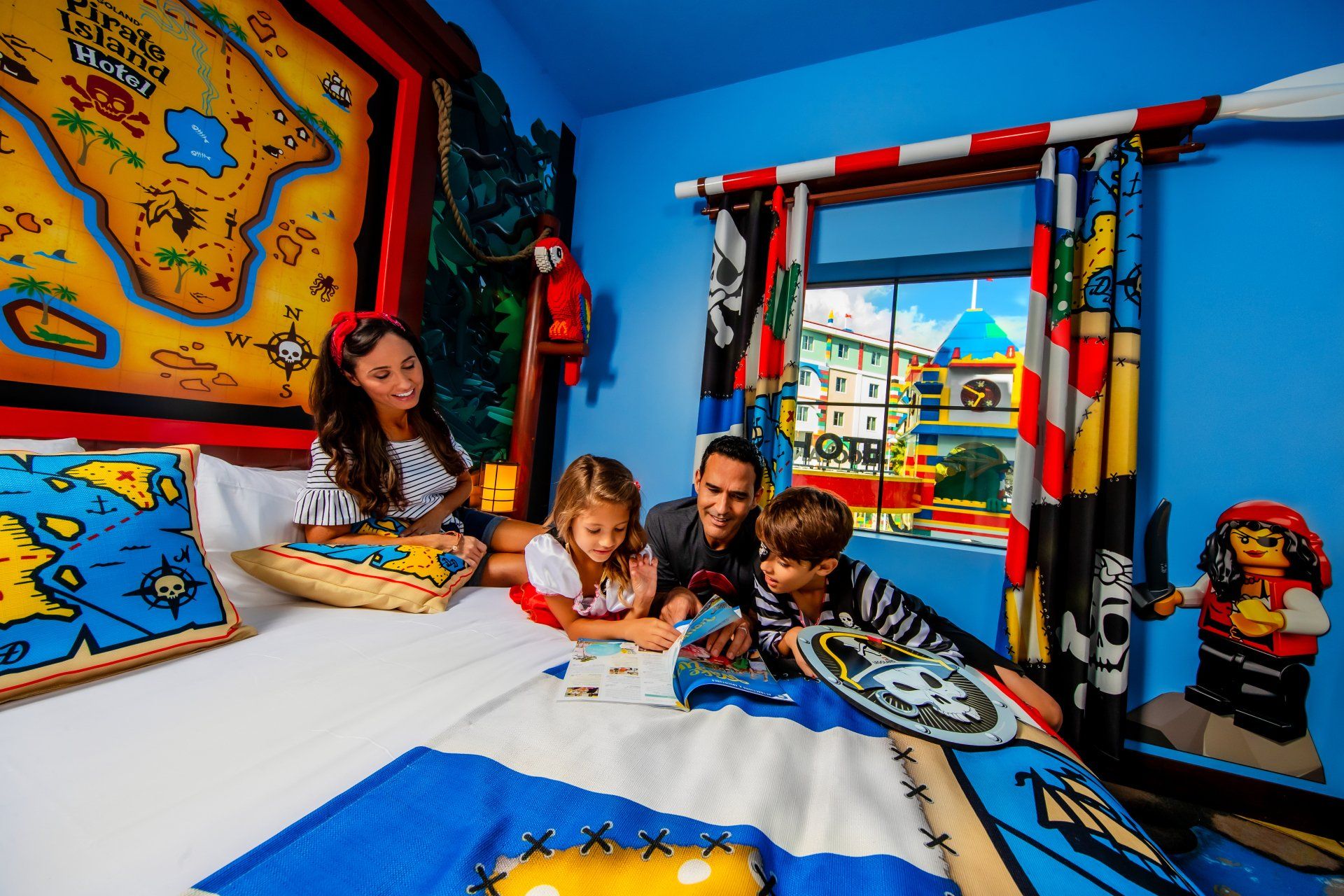 A family is sitting on a bed in a pirate themed room.