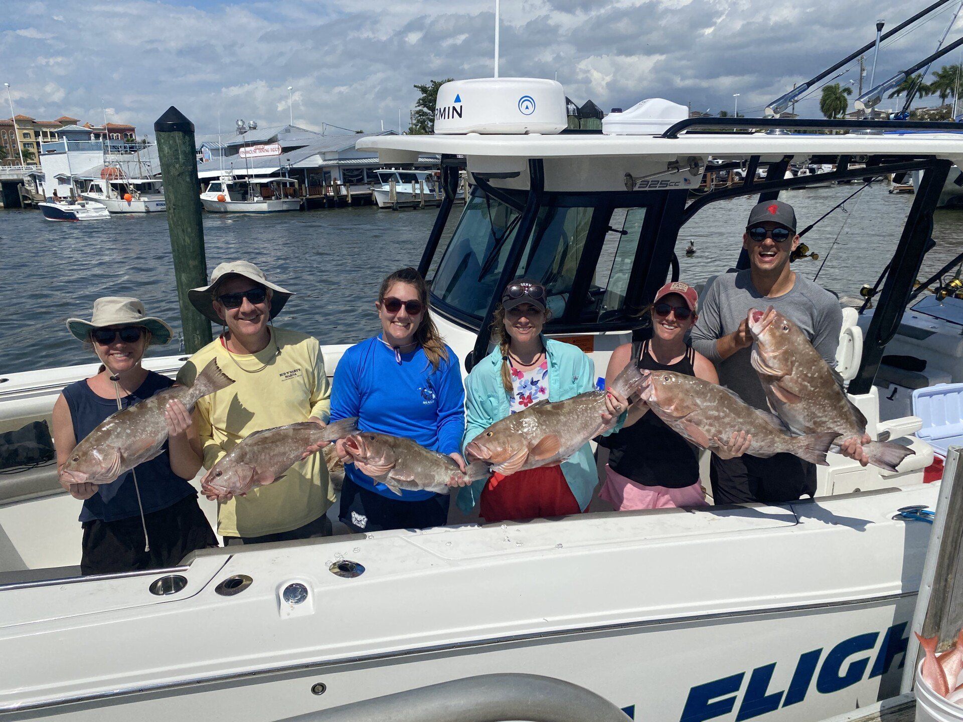 A group of people are standing on a boat holding fish.