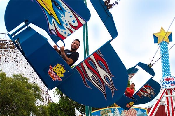 A man is riding a ferris wheel at an amusement park