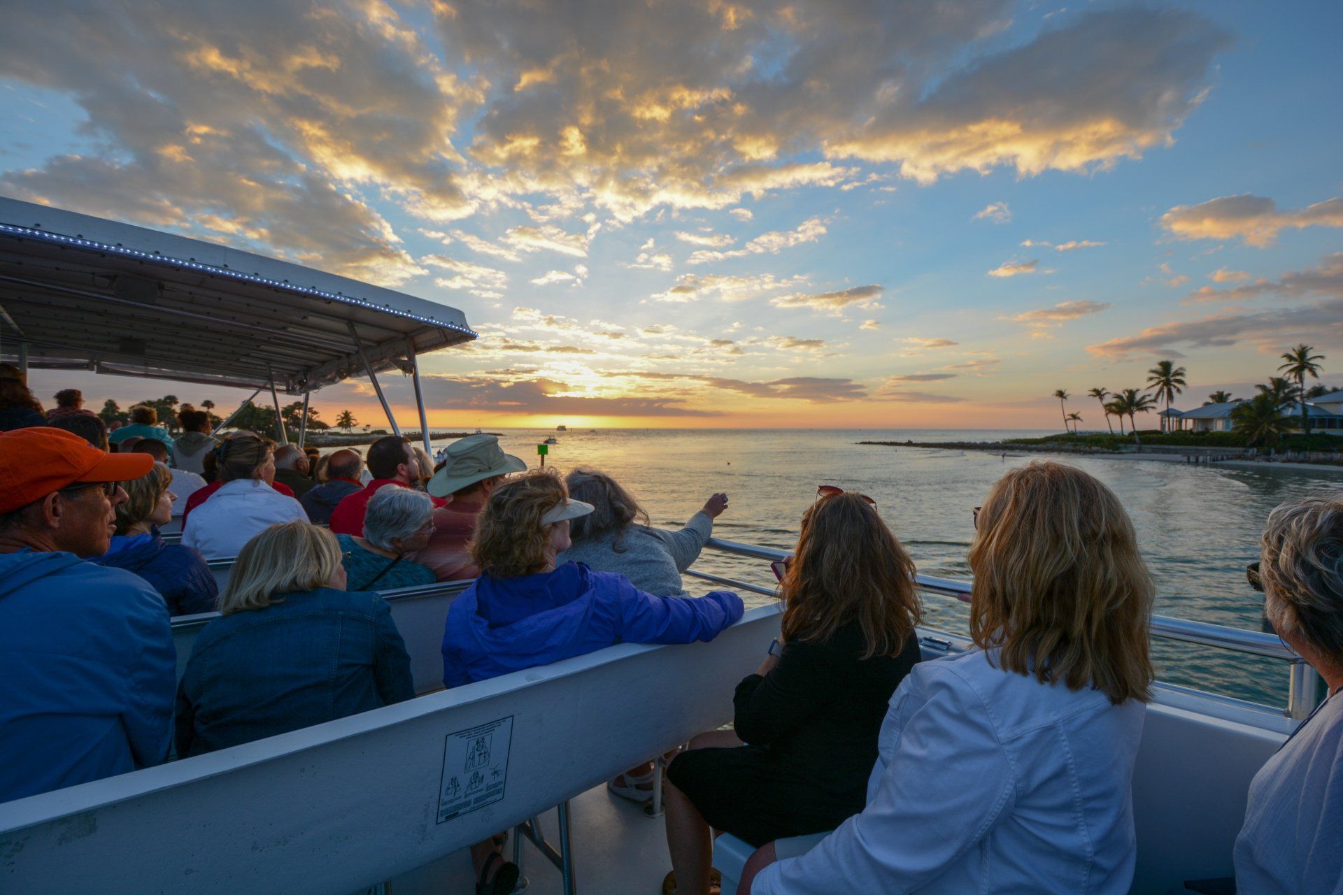 A group of people are sitting on a boat watching the sunset.