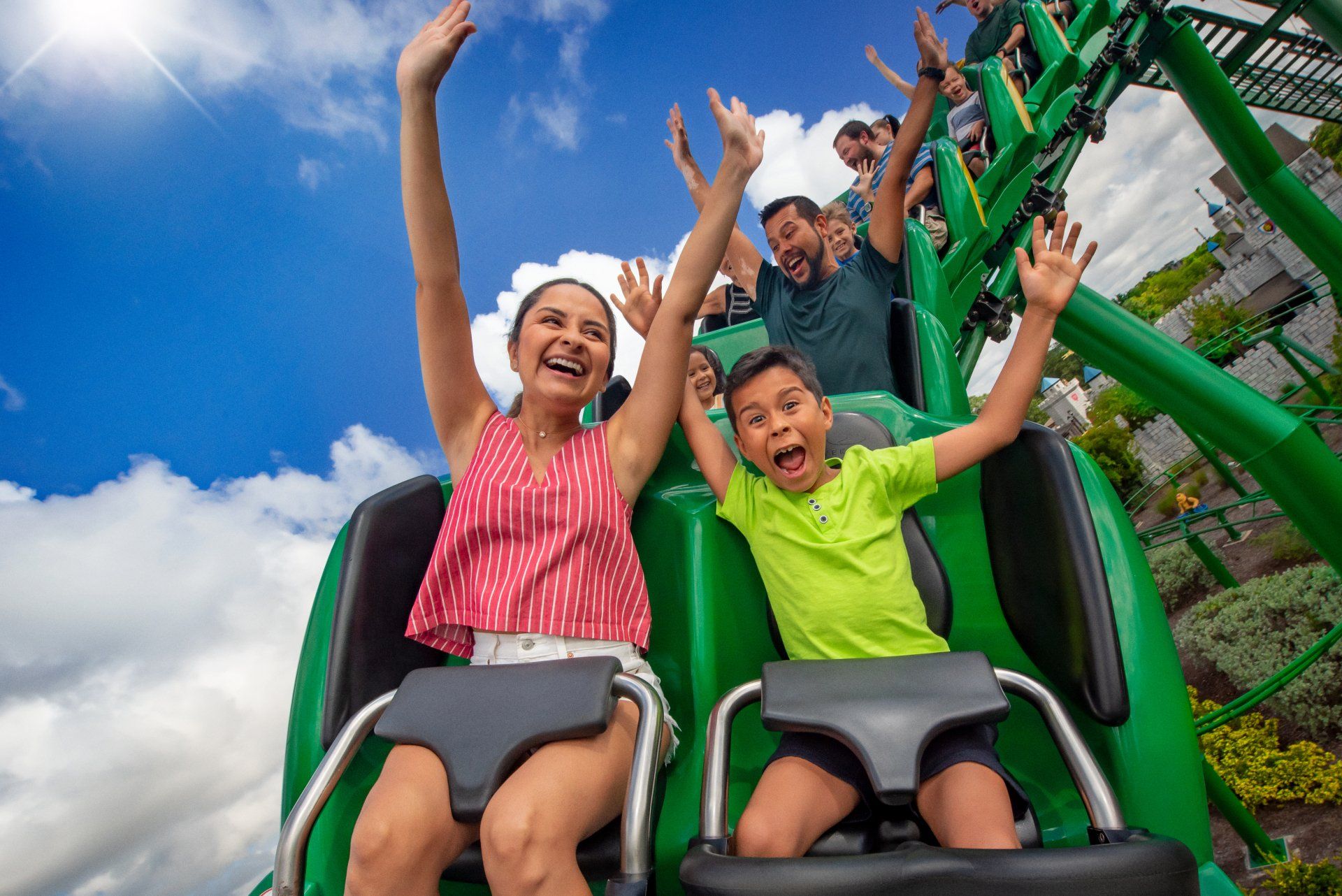 A woman and a boy are riding a roller coaster at an amusement park.