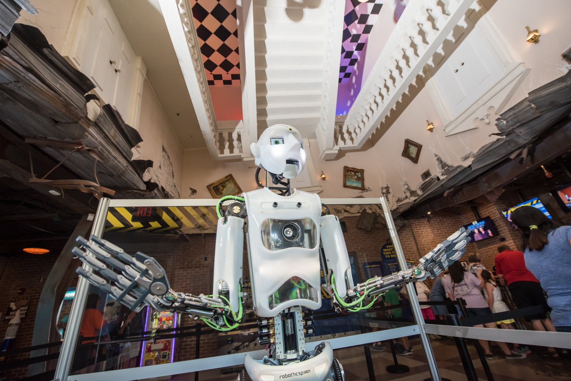 A robot is standing in front of a crowd of people in a room.