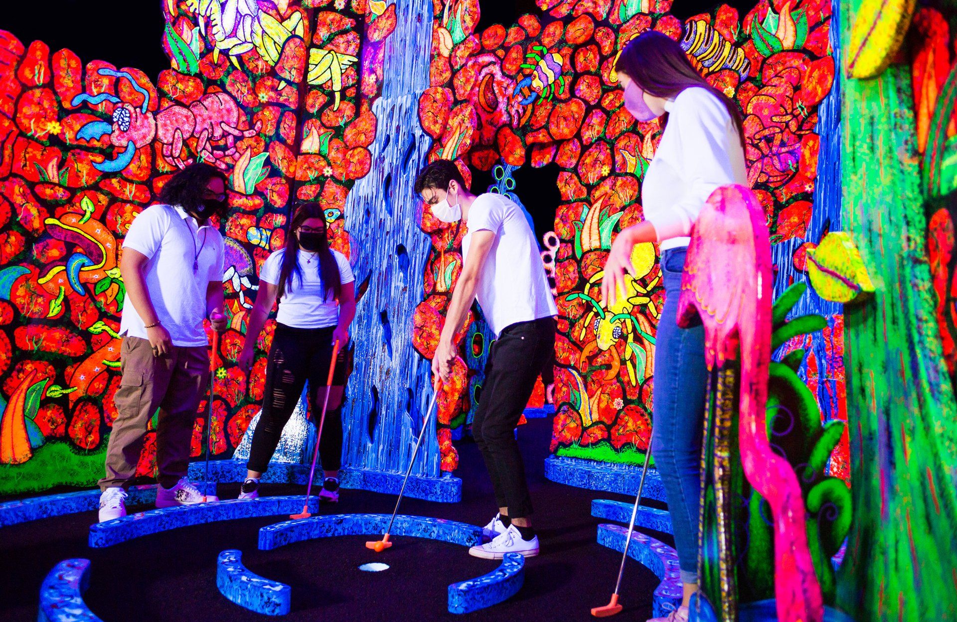 A group of people are playing glow in the dark mini golf.