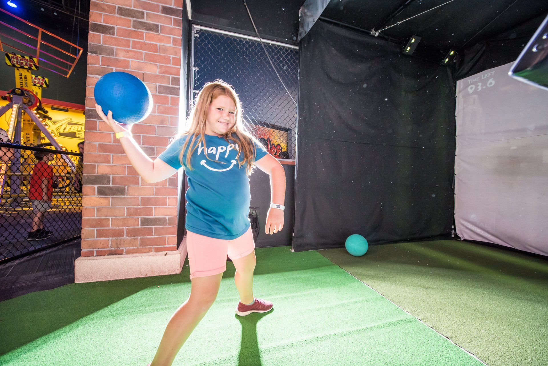 A young girl is holding a blue ball in her hand.