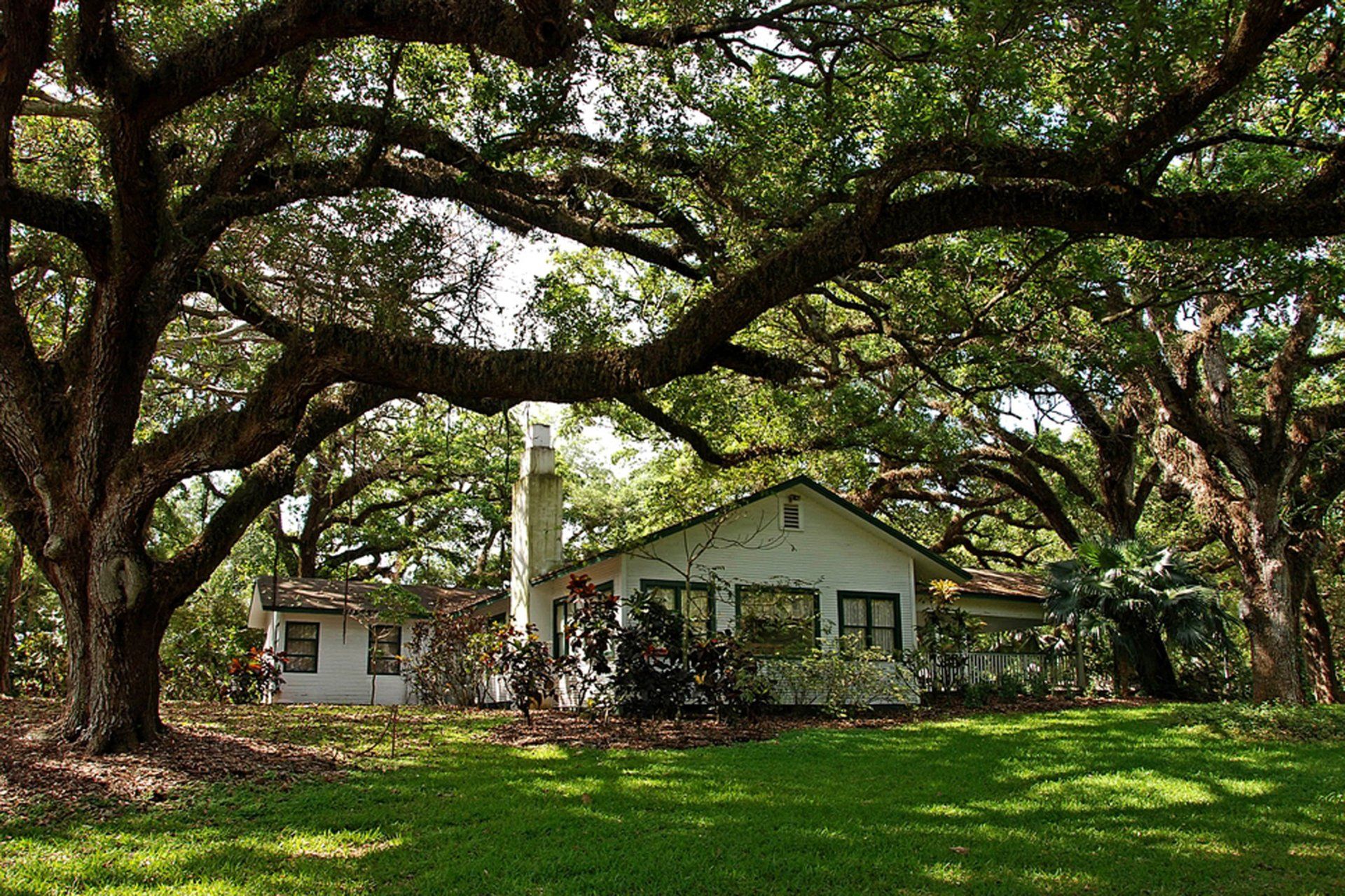 A white house is surrounded by trees and grass