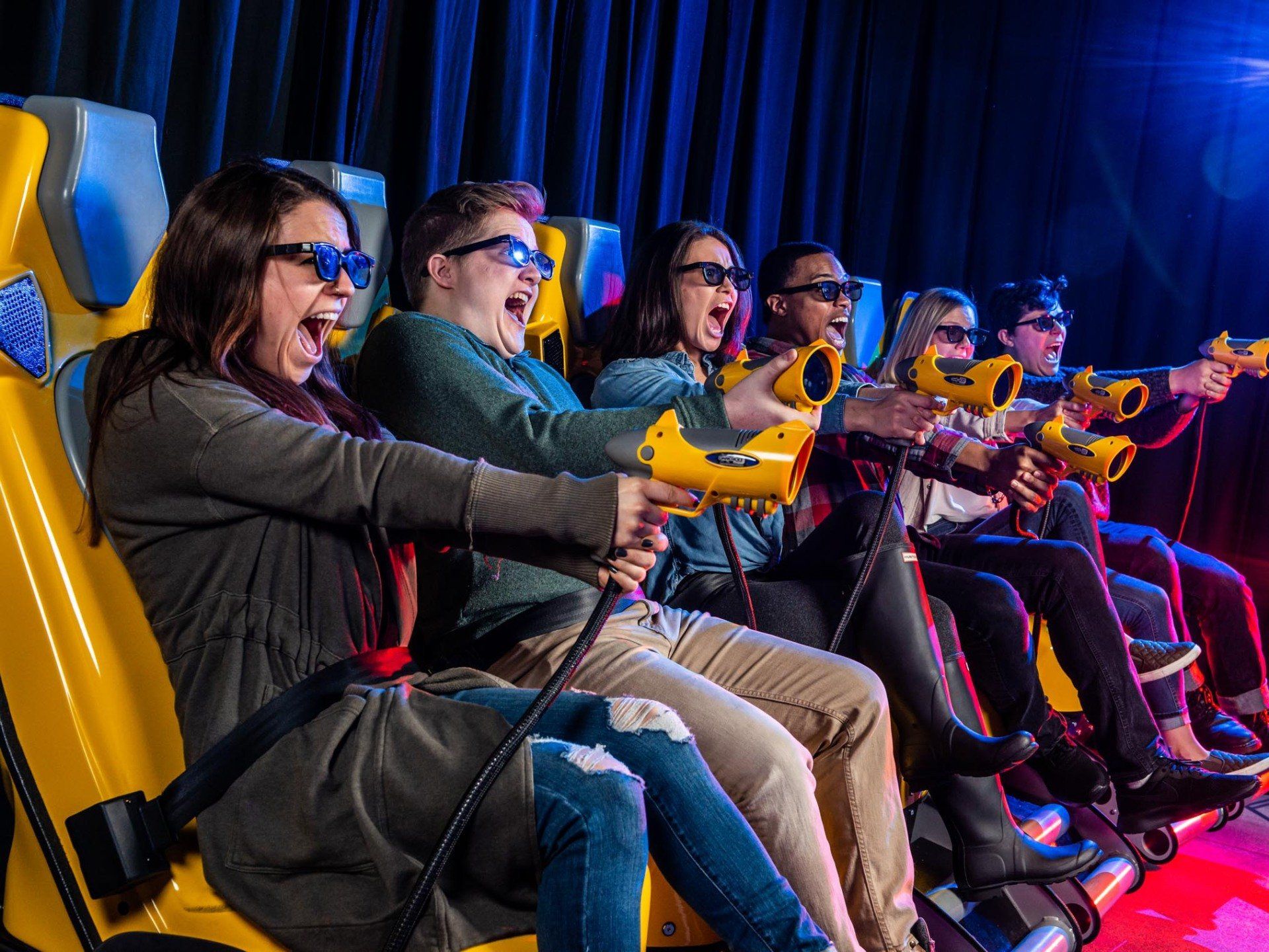 A group of people are sitting on a roller coaster wearing 3d glasses.