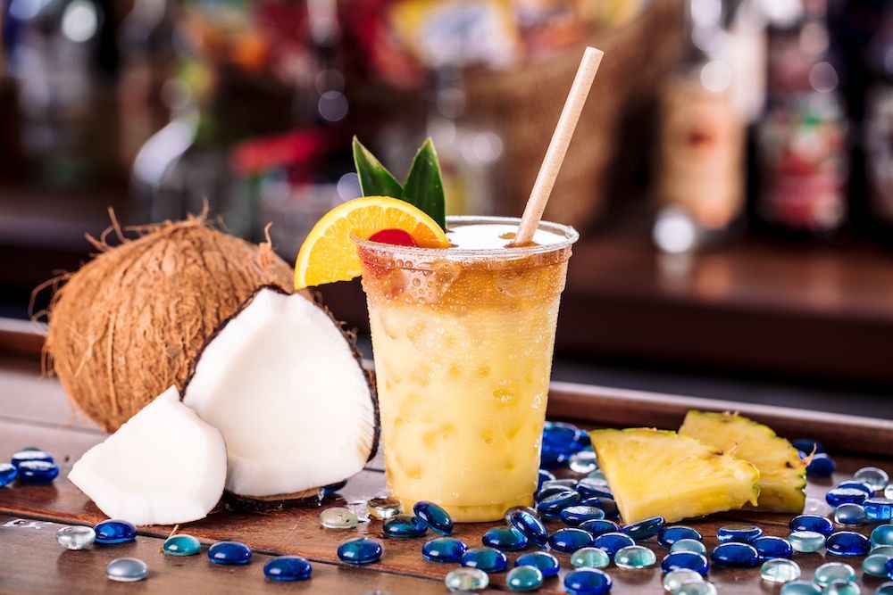 A pineapple and coconut cocktail with a straw on a bar.