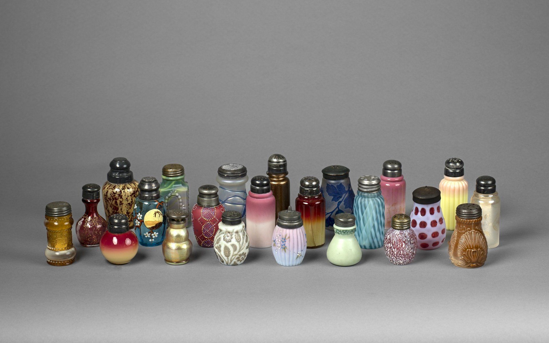 A group of salt and pepper shakers are lined up on a table.