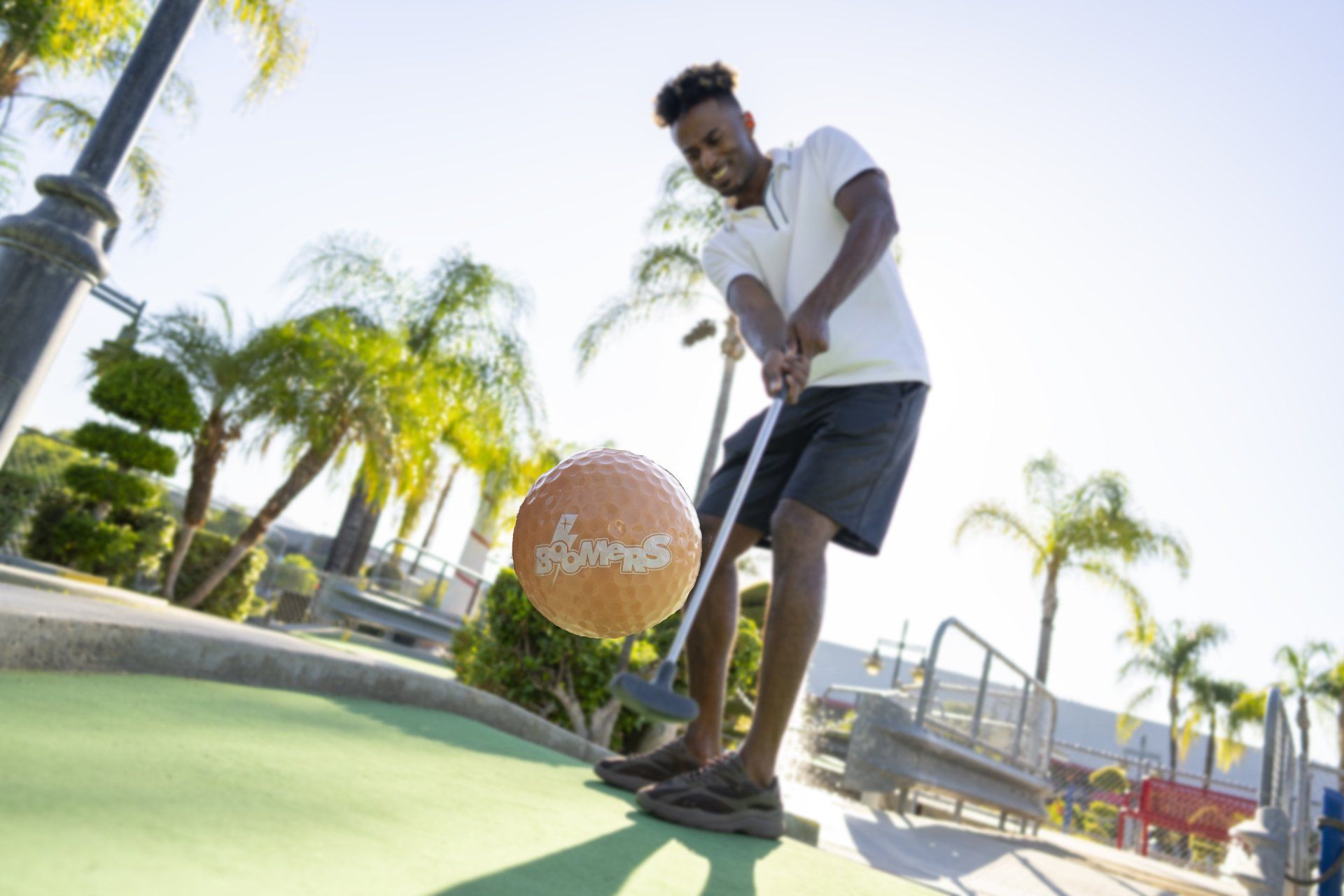 A man is playing mini golf with a basketball in his hand.