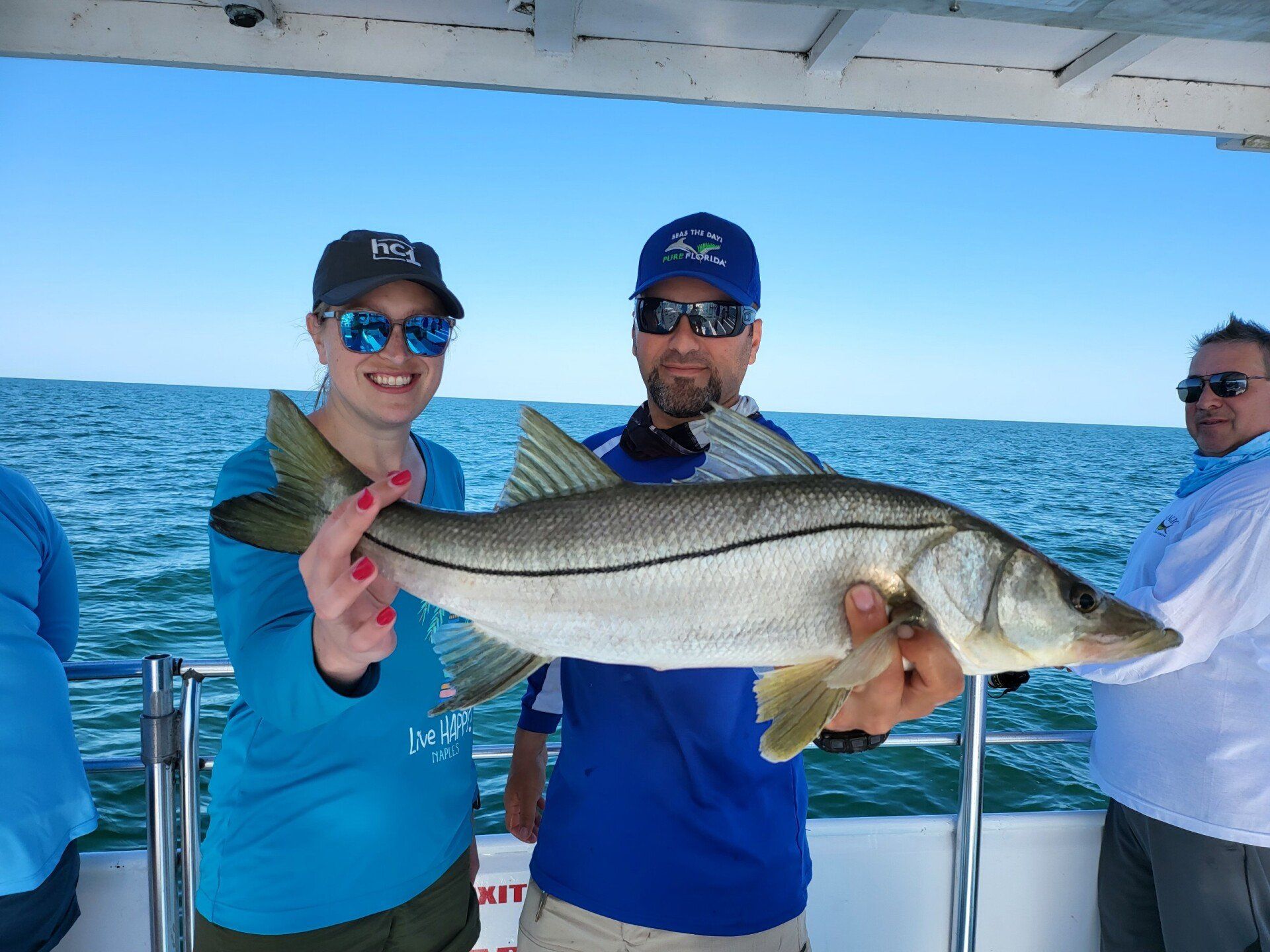 A man and a woman are holding a large fish on a boat.