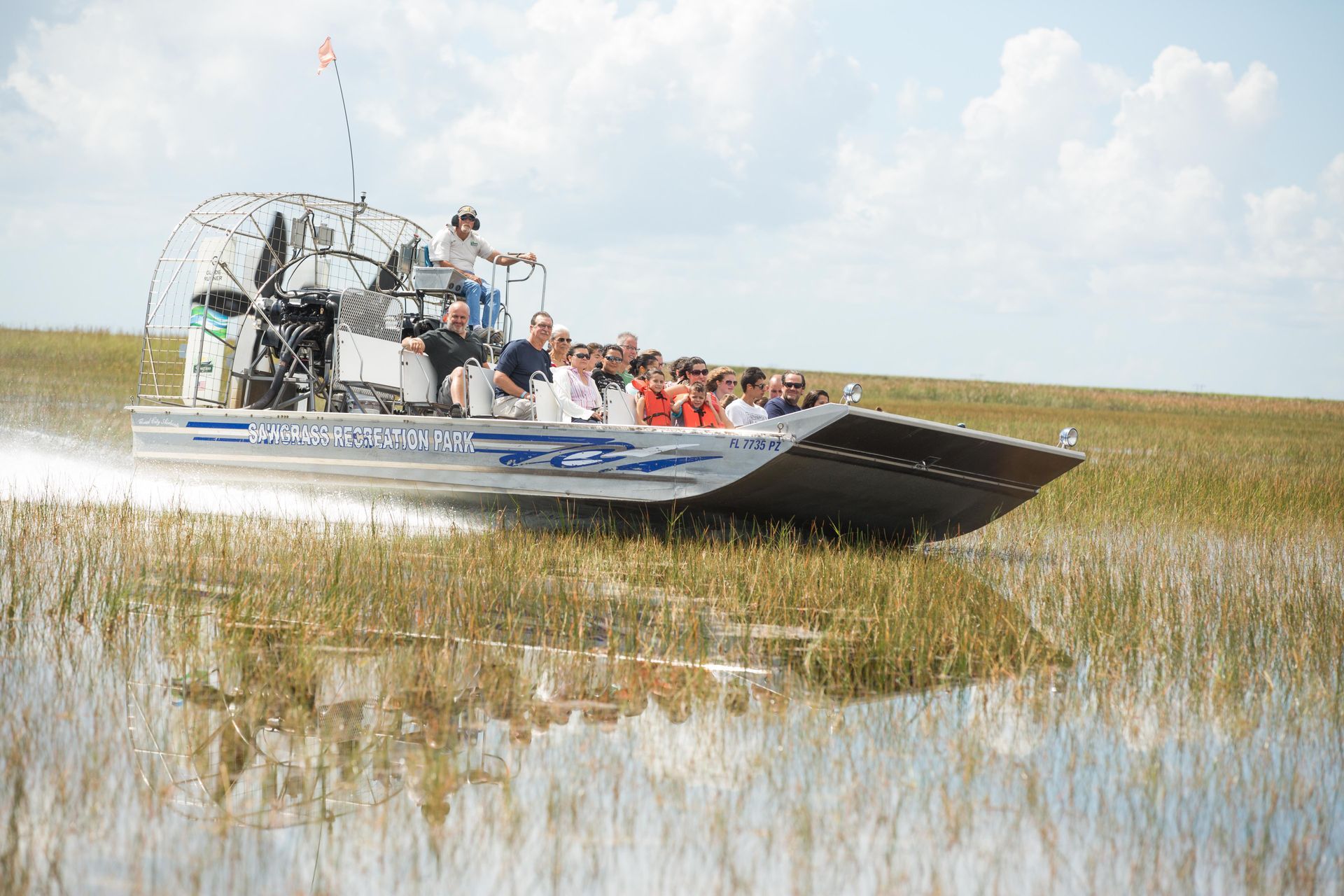 A group of people are riding a boat through a swamp.