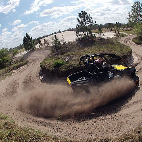 A yellow and black vehicle is driving down a dirt road
