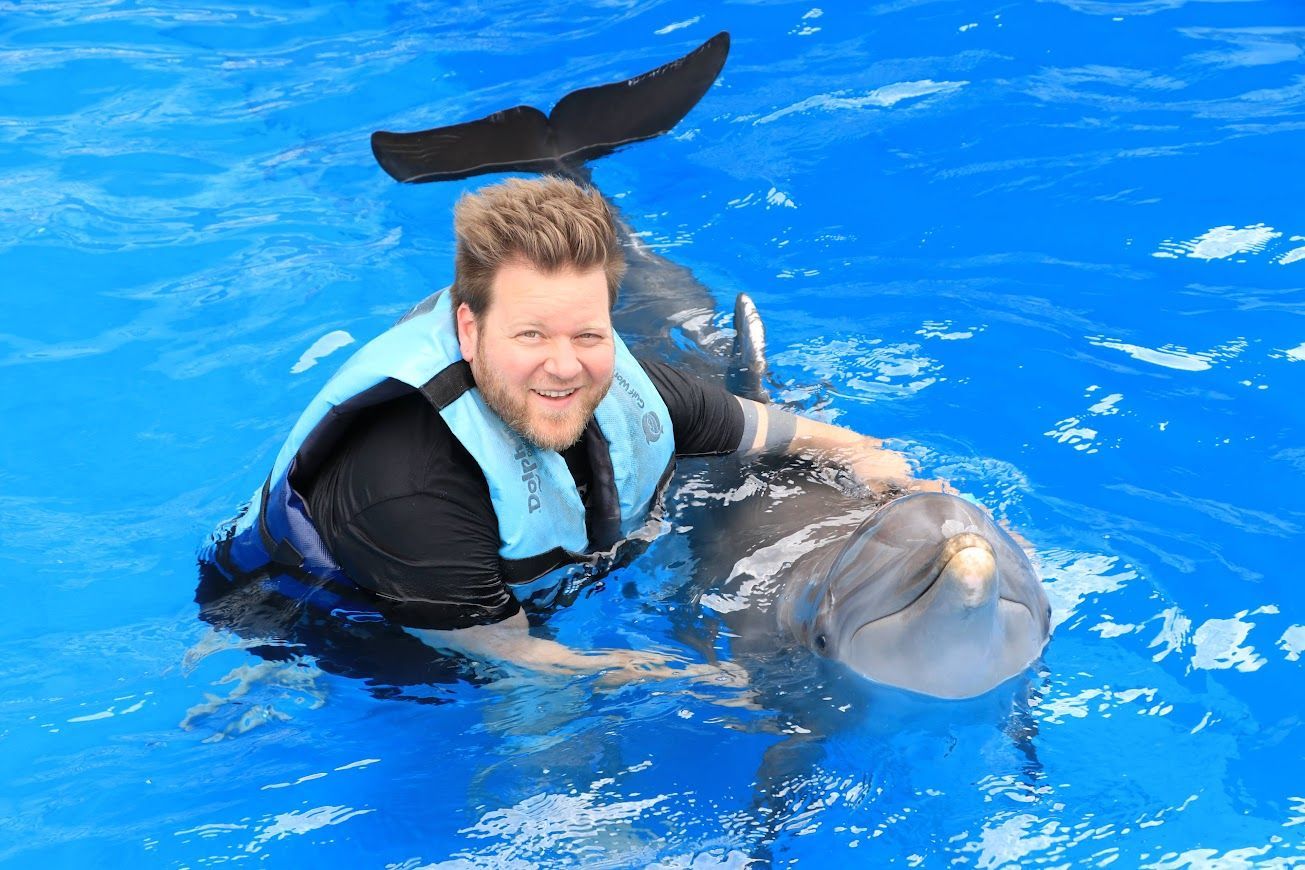 A man is holding a dolphin in the water.