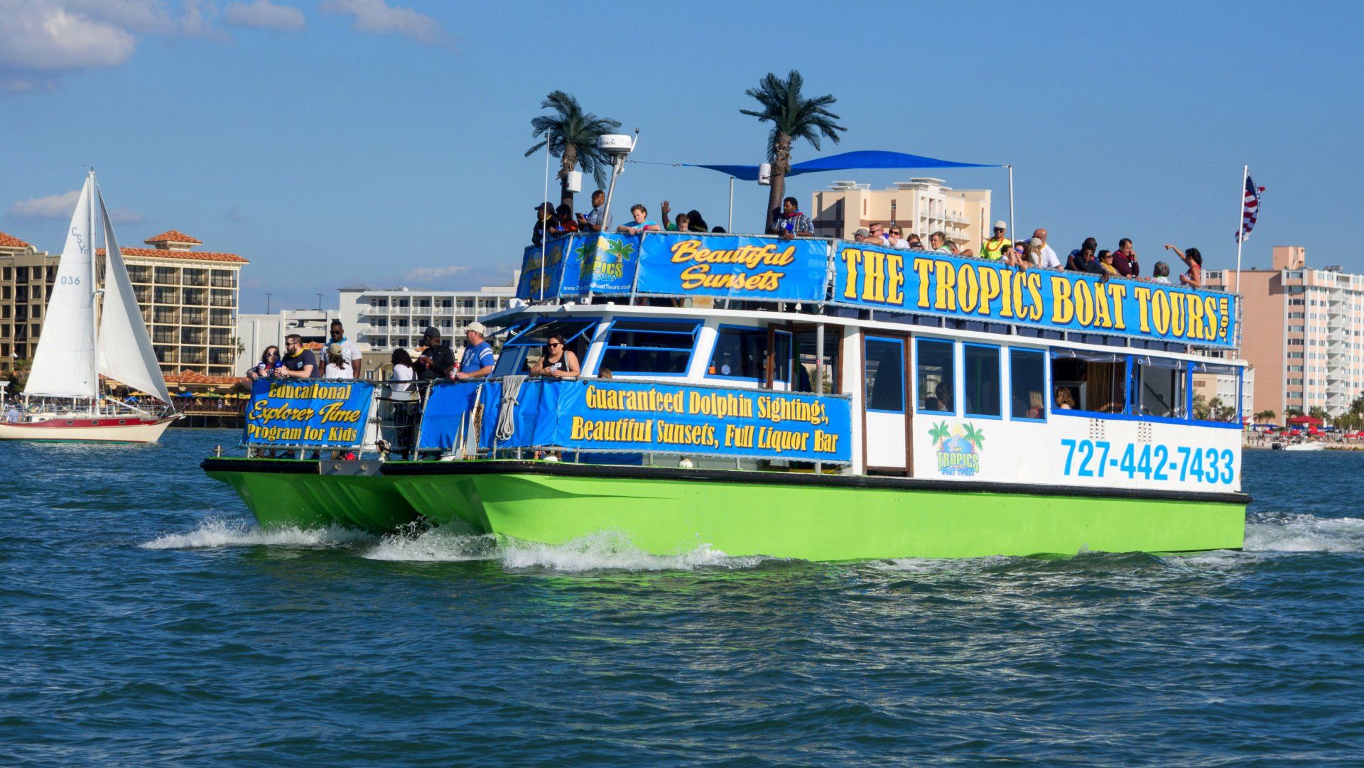 A green boat that says the tropics boat tours on it