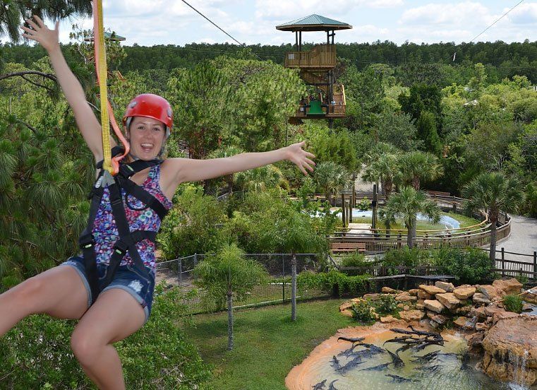 A woman is flying through the air on a zip line.