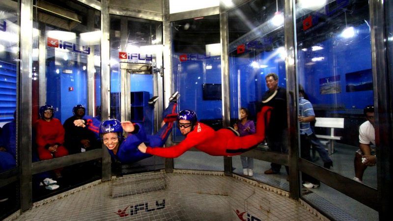 A person in a red suit is flying through the air in a wind tunnel.