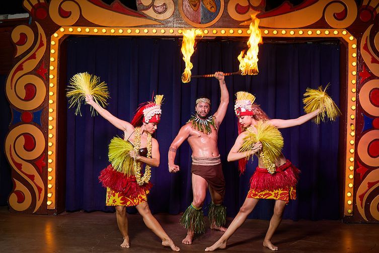 A man and two women are dancing on a stage with flames coming out of their hands.