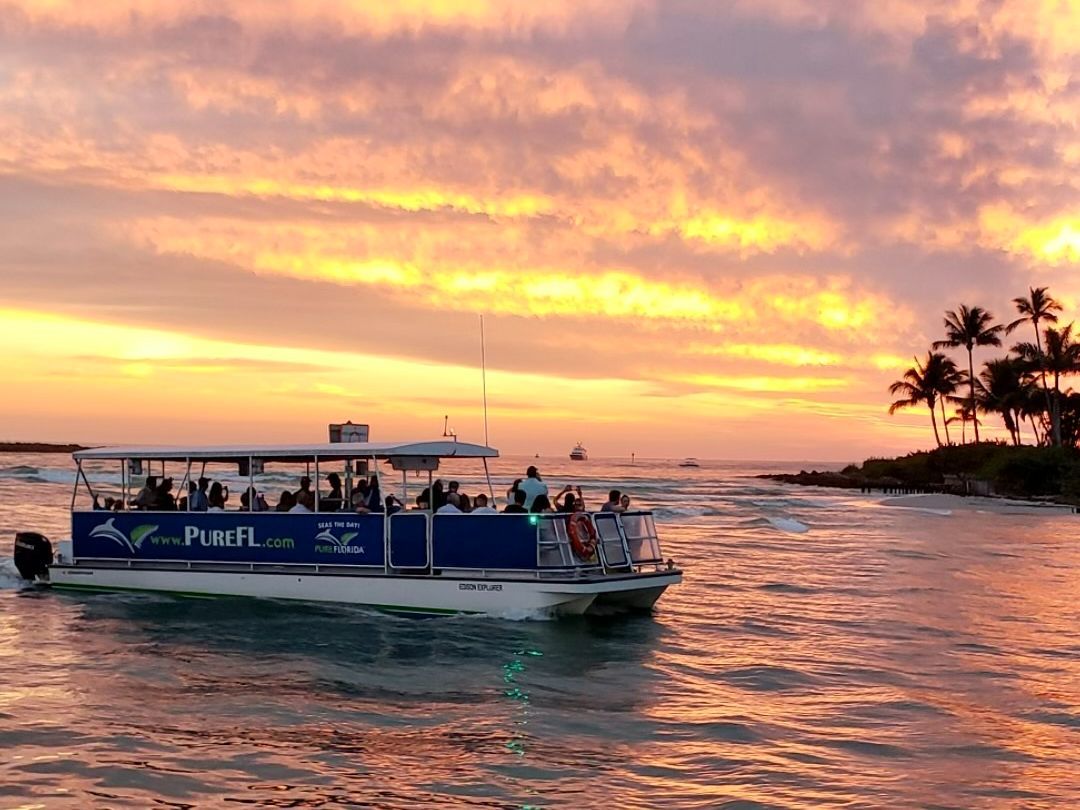 A boat is floating on top of a body of water at sunset.