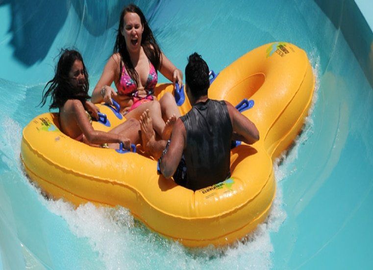A group of people are riding a yellow raft down a water slide.