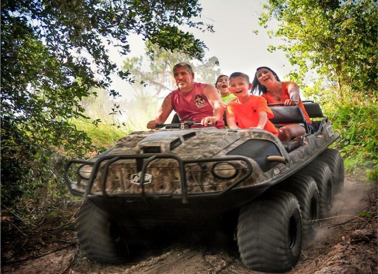 A family is riding on the back of a military vehicle.