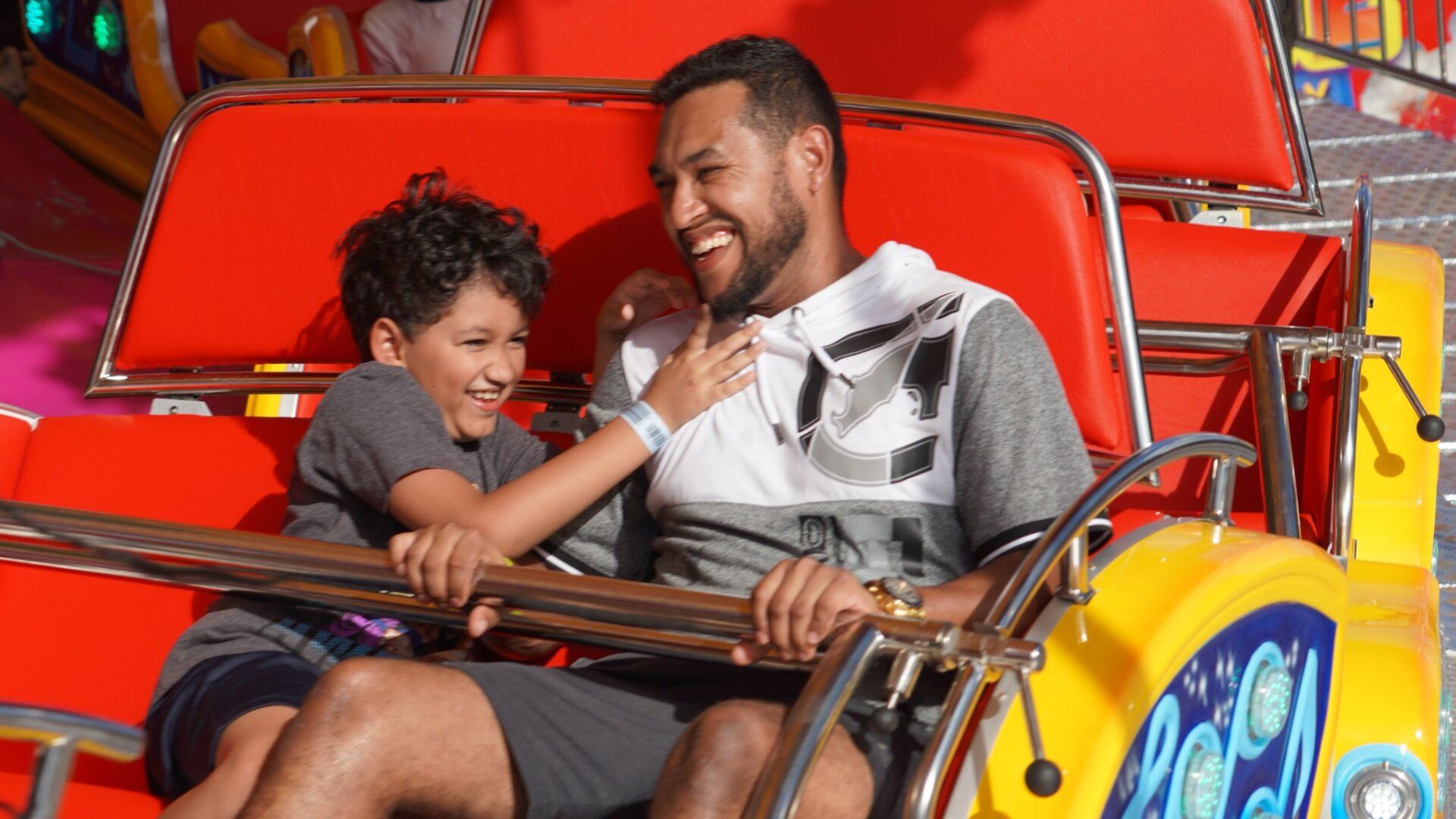 A man and a boy are riding a roller coaster at an amusement park.