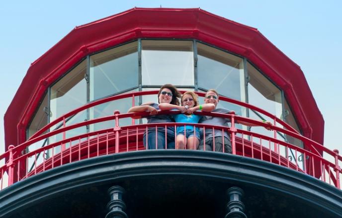A group of people are posing for a picture on top of a lighthouse.
