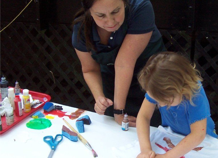 A woman and a little girl are painting on a table