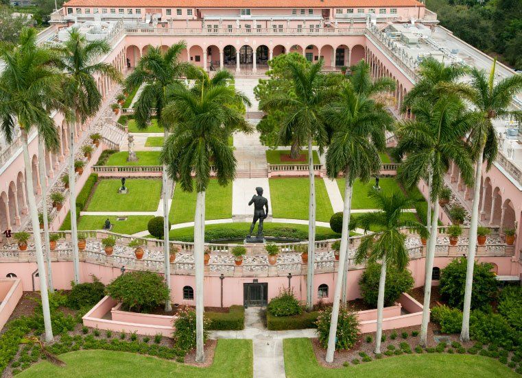An aerial view of a large building surrounded by palm trees