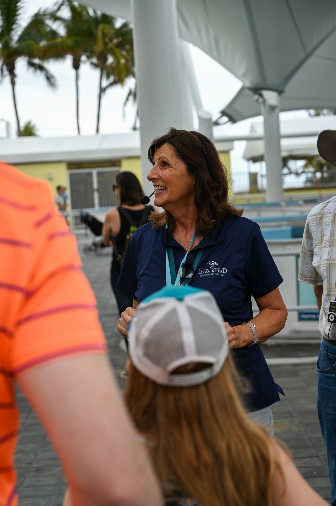 A woman wearing a baseball cap is talking to a group of people.