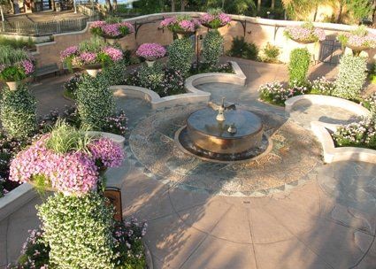 A fountain in a garden surrounded by pink and white flowers